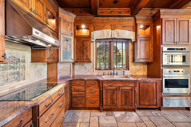 kitchen with black electric stovetop, stone countertops, stainless steel double oven, backsplash, and sink