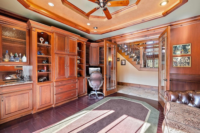 unfurnished office featuring sink, a raised ceiling, dark hardwood / wood-style flooring, ceiling fan, and ornamental molding