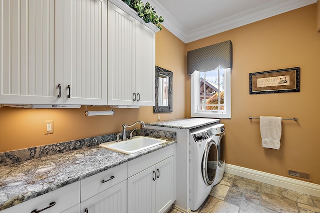 clothes washing area featuring ornamental molding, sink, cabinets, and washer and clothes dryer