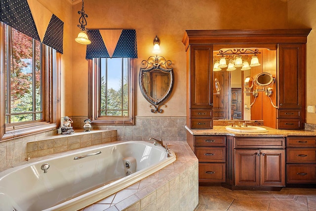 bathroom with vanity, tile patterned flooring, tiled tub, and a wealth of natural light