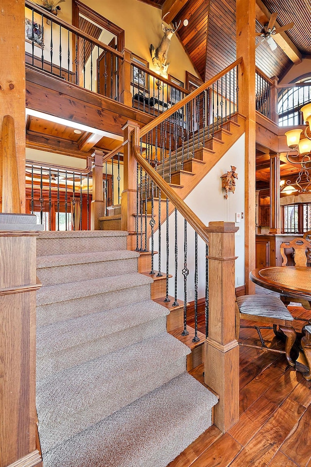 stairs featuring beam ceiling, high vaulted ceiling, and wood-type flooring