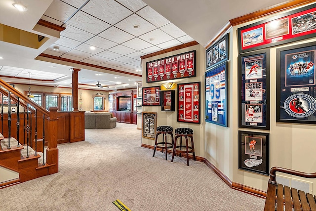 interior space with a raised ceiling, decorative columns, light carpet, ceiling fan, and crown molding