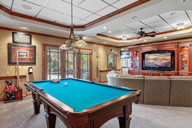 recreation room with ceiling fan, ornamental molding, a tray ceiling, and light colored carpet