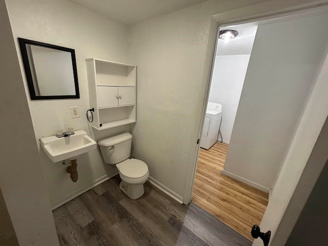 bathroom with washer / dryer, hardwood / wood-style flooring, toilet, and sink