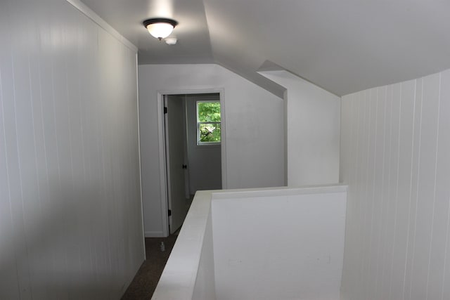 corridor featuring wood walls and vaulted ceiling