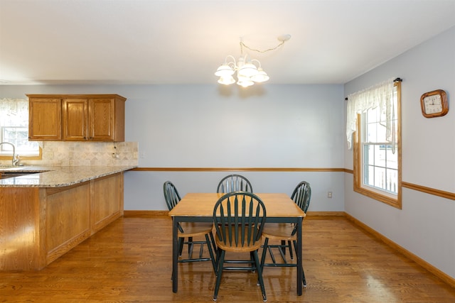 dining room featuring a healthy amount of sunlight, hardwood / wood-style flooring, sink, and a chandelier