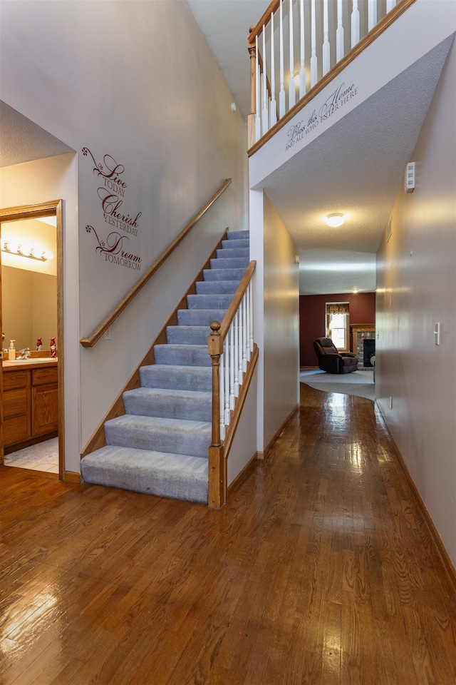 stairway with a textured ceiling, sink, and hardwood / wood-style floors