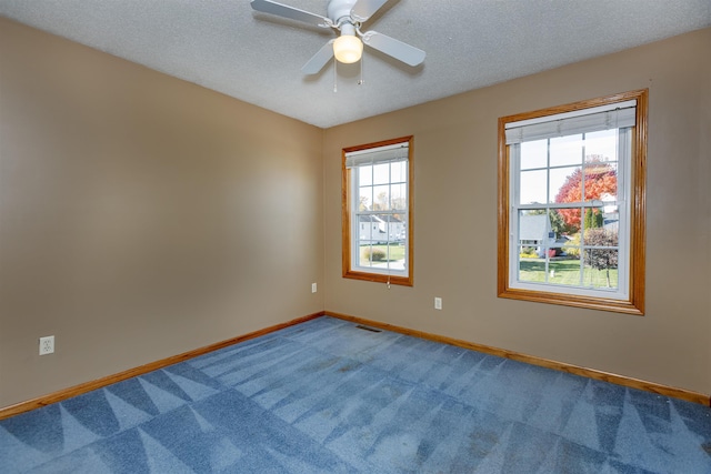 carpeted spare room featuring a textured ceiling, a healthy amount of sunlight, and ceiling fan