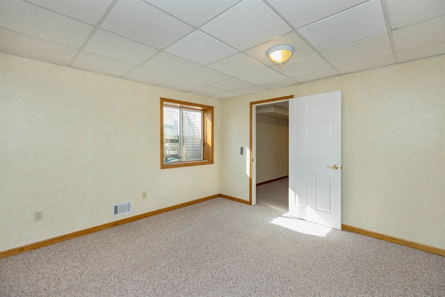 empty room with carpet flooring and a drop ceiling