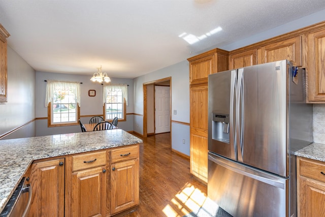 kitchen with light hardwood / wood-style flooring, a notable chandelier, decorative light fixtures, appliances with stainless steel finishes, and light stone counters