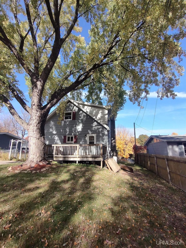 rear view of house with a wooden deck and a lawn