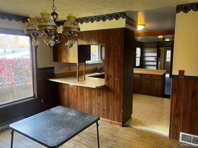 kitchen featuring light hardwood / wood-style flooring, a wealth of natural light, kitchen peninsula, and an inviting chandelier