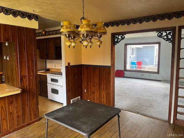 kitchen with dark brown cabinetry, a textured ceiling, white range oven, and a chandelier