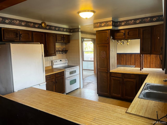 kitchen with white appliances, tasteful backsplash, dark brown cabinets, and sink