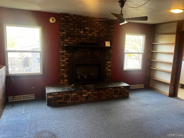 unfurnished living room featuring a textured ceiling, ceiling fan, carpet flooring, and a brick fireplace