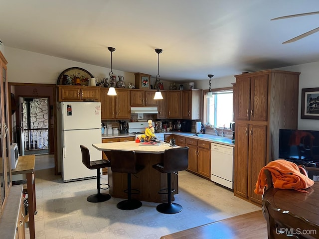 kitchen with hanging light fixtures, backsplash, vaulted ceiling, a center island, and white appliances