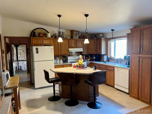 kitchen featuring white appliances, tasteful backsplash, sink, a kitchen island, and hanging light fixtures