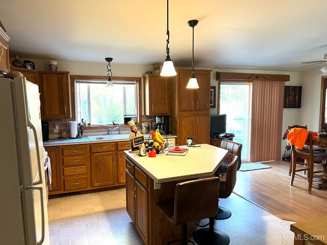 kitchen featuring a healthy amount of sunlight, decorative light fixtures, a kitchen island, and white refrigerator