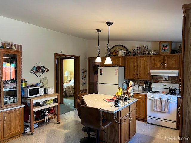 kitchen featuring white appliances, a kitchen island, pendant lighting, decorative backsplash, and a breakfast bar