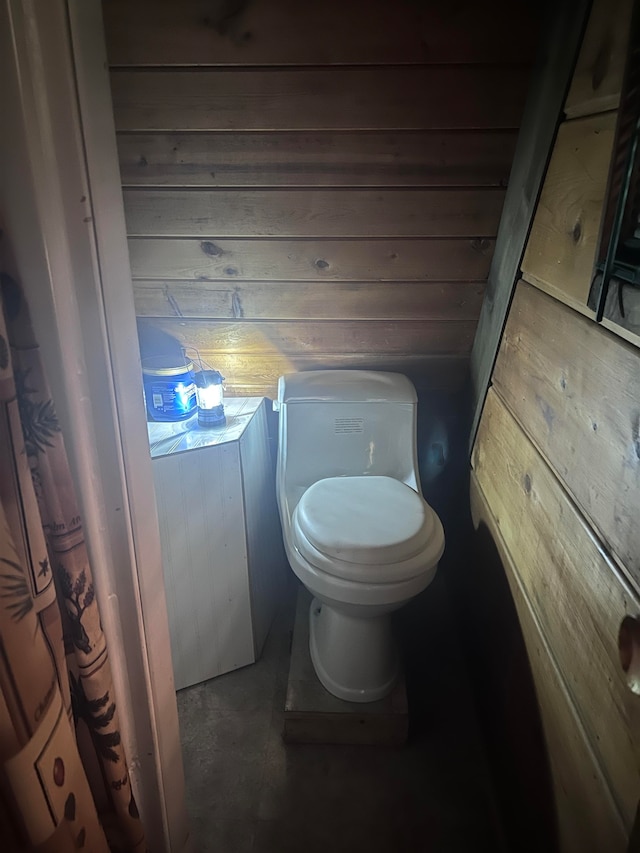 bathroom featuring wooden walls and toilet