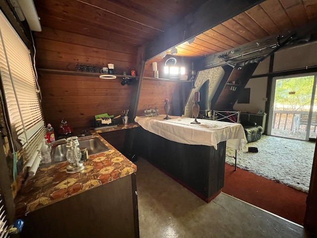 interior space with wood ceiling, wooden walls, sink, and concrete floors