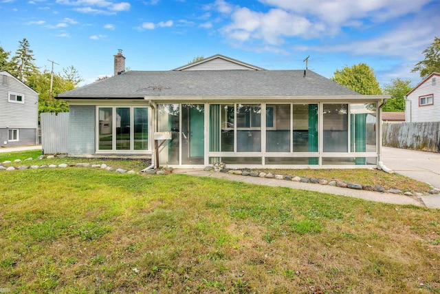 back of property with a lawn and a sunroom