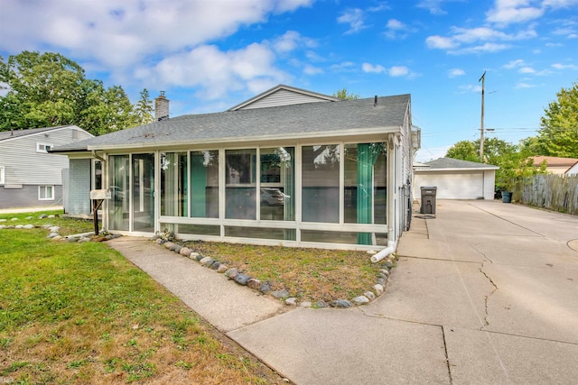 view of front of property with a front yard, a garage, an outbuilding, and a sunroom