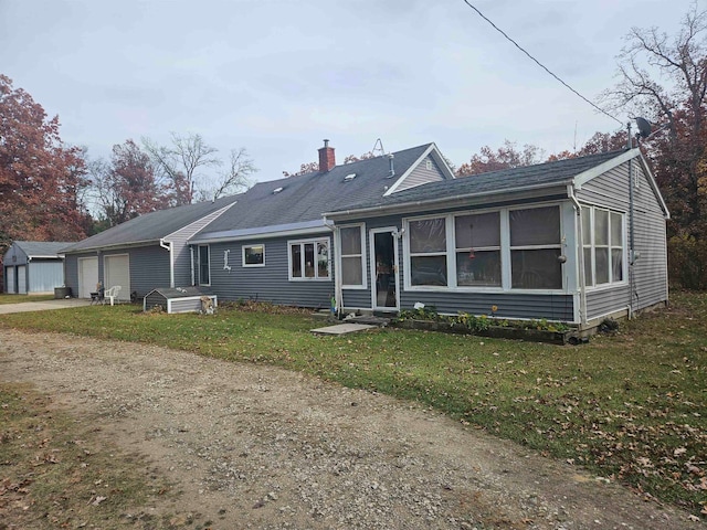 view of front facade with an attached garage, a chimney, and a front yard