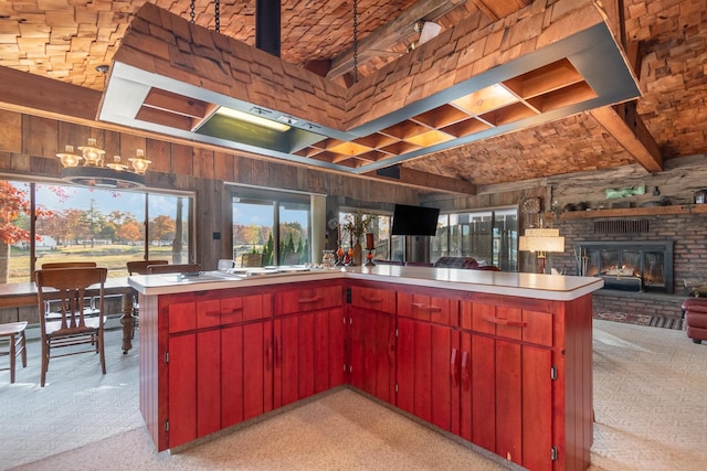 kitchen with beam ceiling, wooden walls, light carpet, kitchen peninsula, and stainless steel gas stovetop