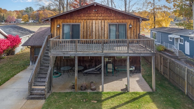 back of property with a wooden deck and a lawn