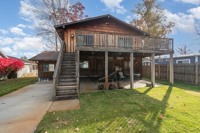 rear view of house with a patio area, a wooden deck, and a lawn