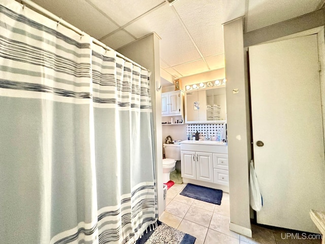 bathroom with vanity, toilet, tile patterned floors, and a paneled ceiling