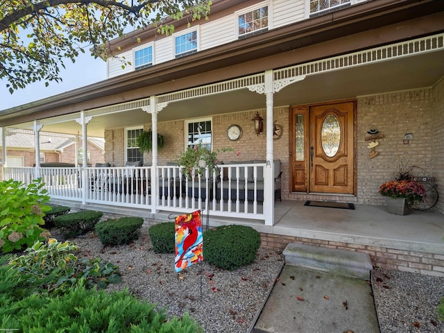 doorway to property with covered porch and brick siding