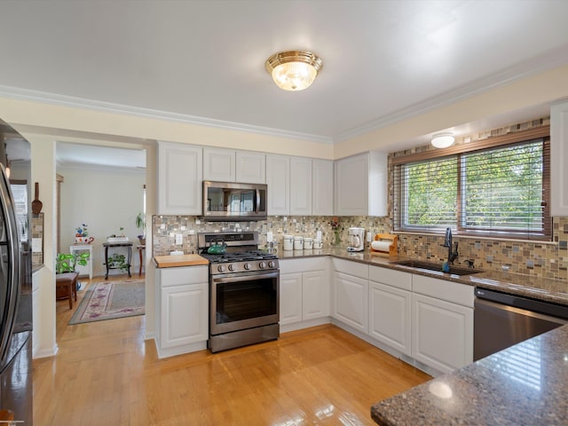 kitchen featuring appliances with stainless steel finishes, white cabinets, tasteful backsplash, and sink