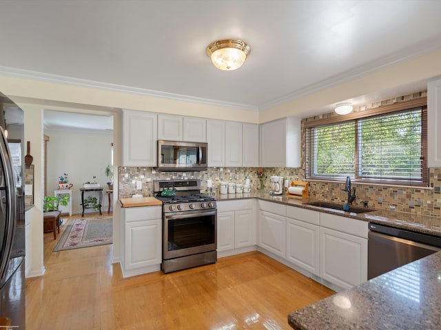 kitchen featuring a sink, decorative backsplash, ornamental molding, and stainless steel appliances