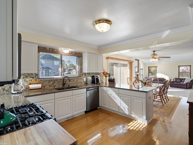 kitchen with stainless steel dishwasher, kitchen peninsula, white cabinetry, and sink