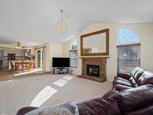 living room featuring carpet floors, ceiling fan with notable chandelier, vaulted ceiling, and a brick fireplace