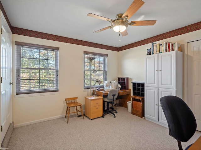carpeted office space featuring baseboards, ceiling fan, and a wealth of natural light