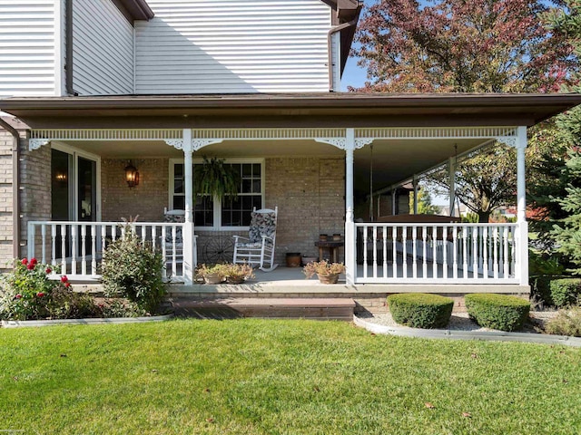 rear view of property featuring a lawn and a porch