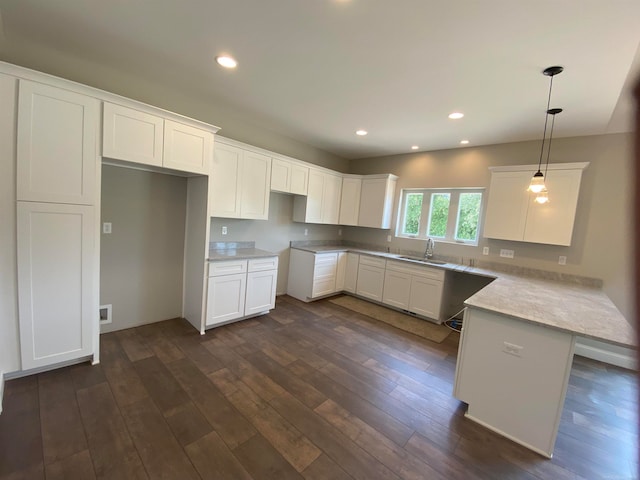 kitchen featuring white cabinets, dark hardwood / wood-style flooring, hanging light fixtures, and sink