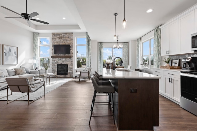 kitchen featuring hanging light fixtures, stainless steel appliances, a center island with sink, sink, and white cabinets