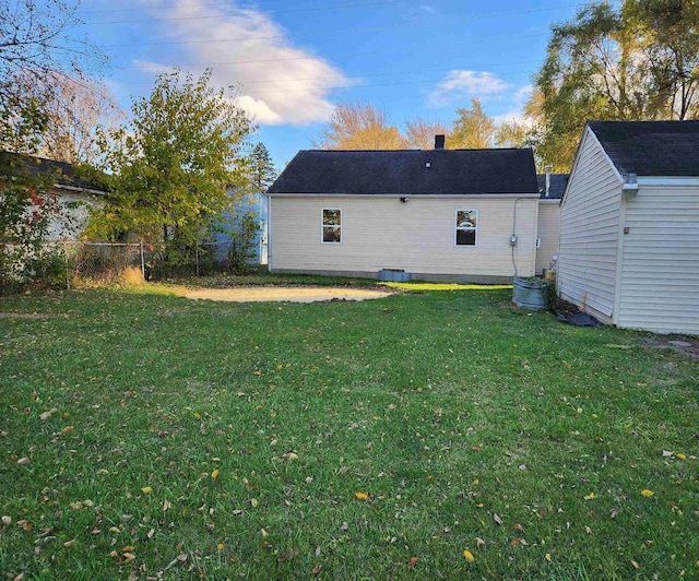 rear view of house with a yard and a storage unit