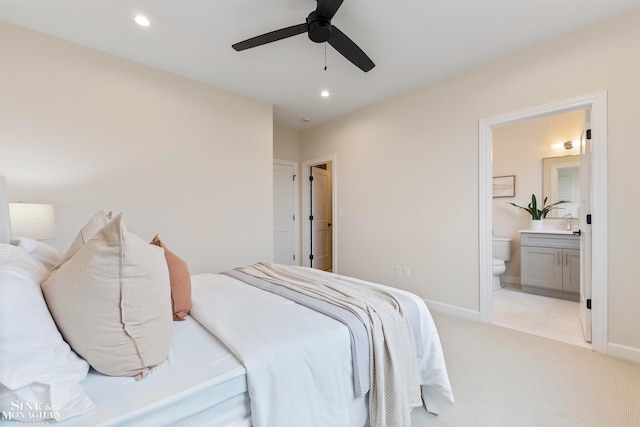 bedroom featuring light carpet, ensuite bathroom, and ceiling fan