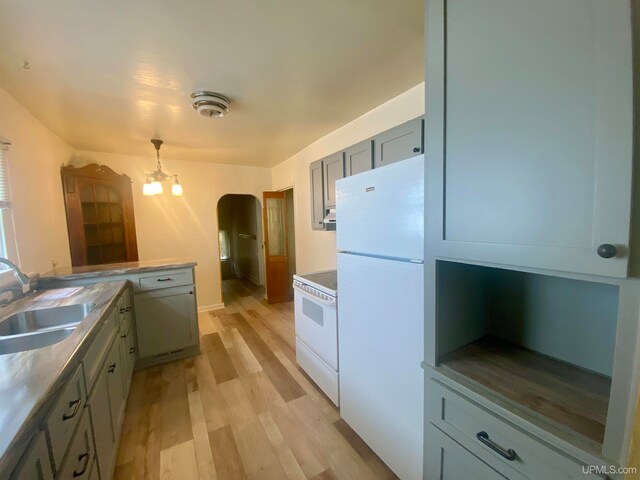 kitchen featuring white appliances, sink, a notable chandelier, pendant lighting, and light hardwood / wood-style floors