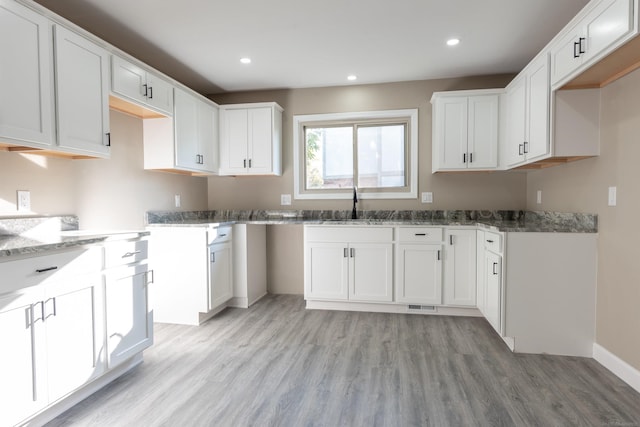 kitchen featuring sink, white cabinets, light wood-type flooring, and stone countertops