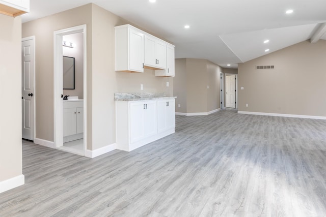 kitchen with light stone countertops, white cabinetry, and light wood-type flooring