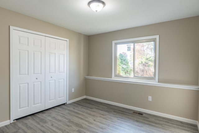 unfurnished bedroom with light hardwood / wood-style flooring and a closet