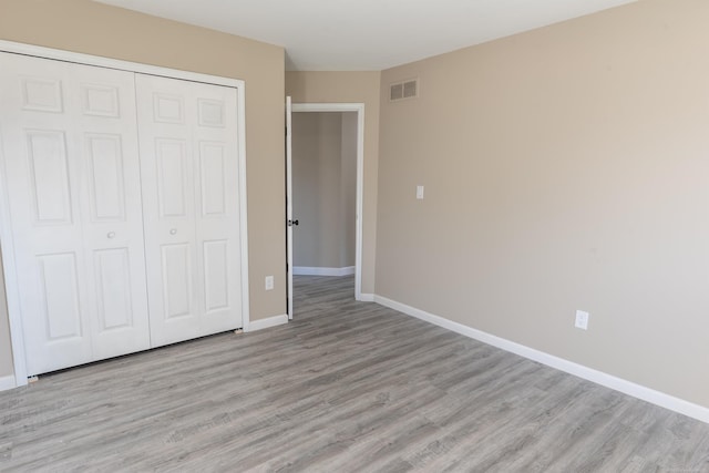 unfurnished bedroom with light hardwood / wood-style flooring and a closet