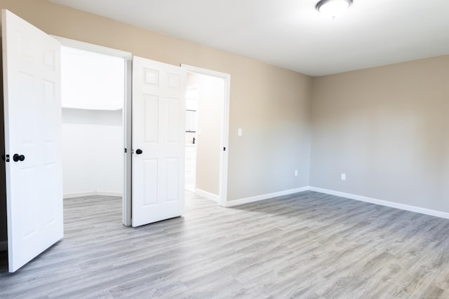 unfurnished bedroom with light hardwood / wood-style flooring, a closet, and a walk in closet