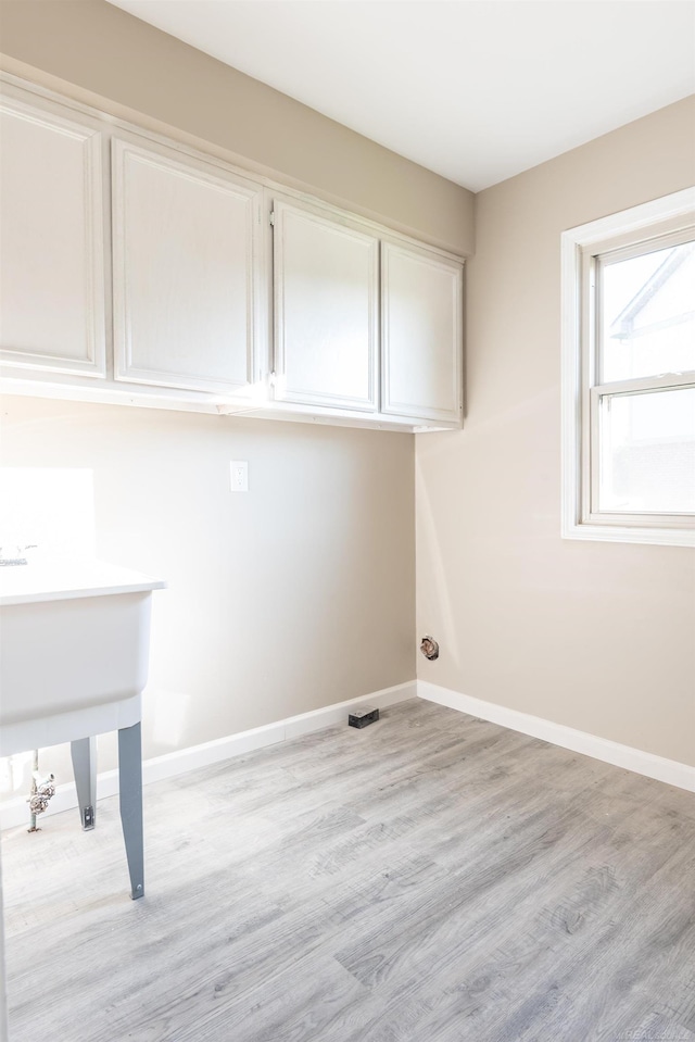 laundry area featuring light hardwood / wood-style flooring and cabinets